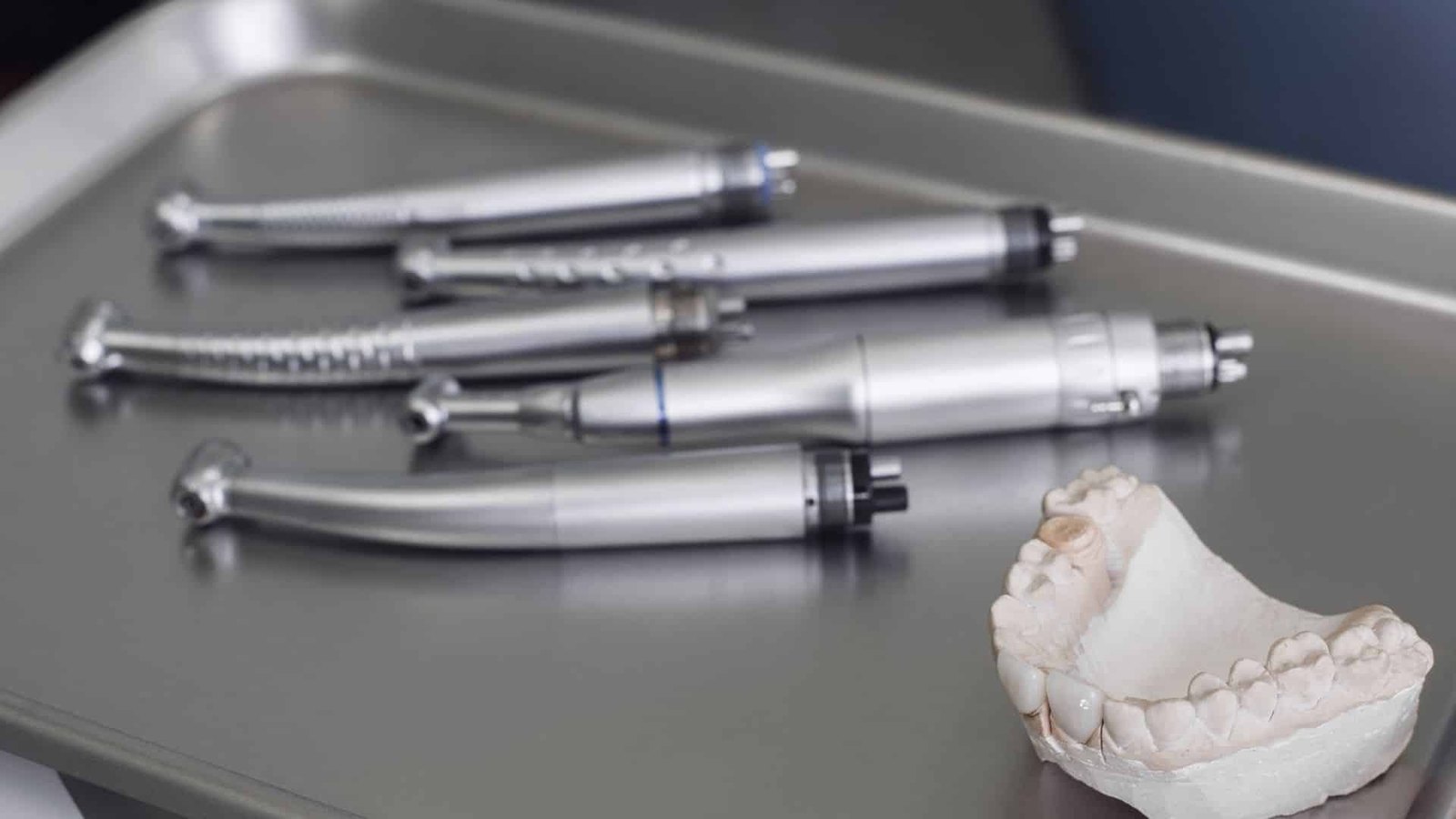 Handpieces on a tray next to a dental model